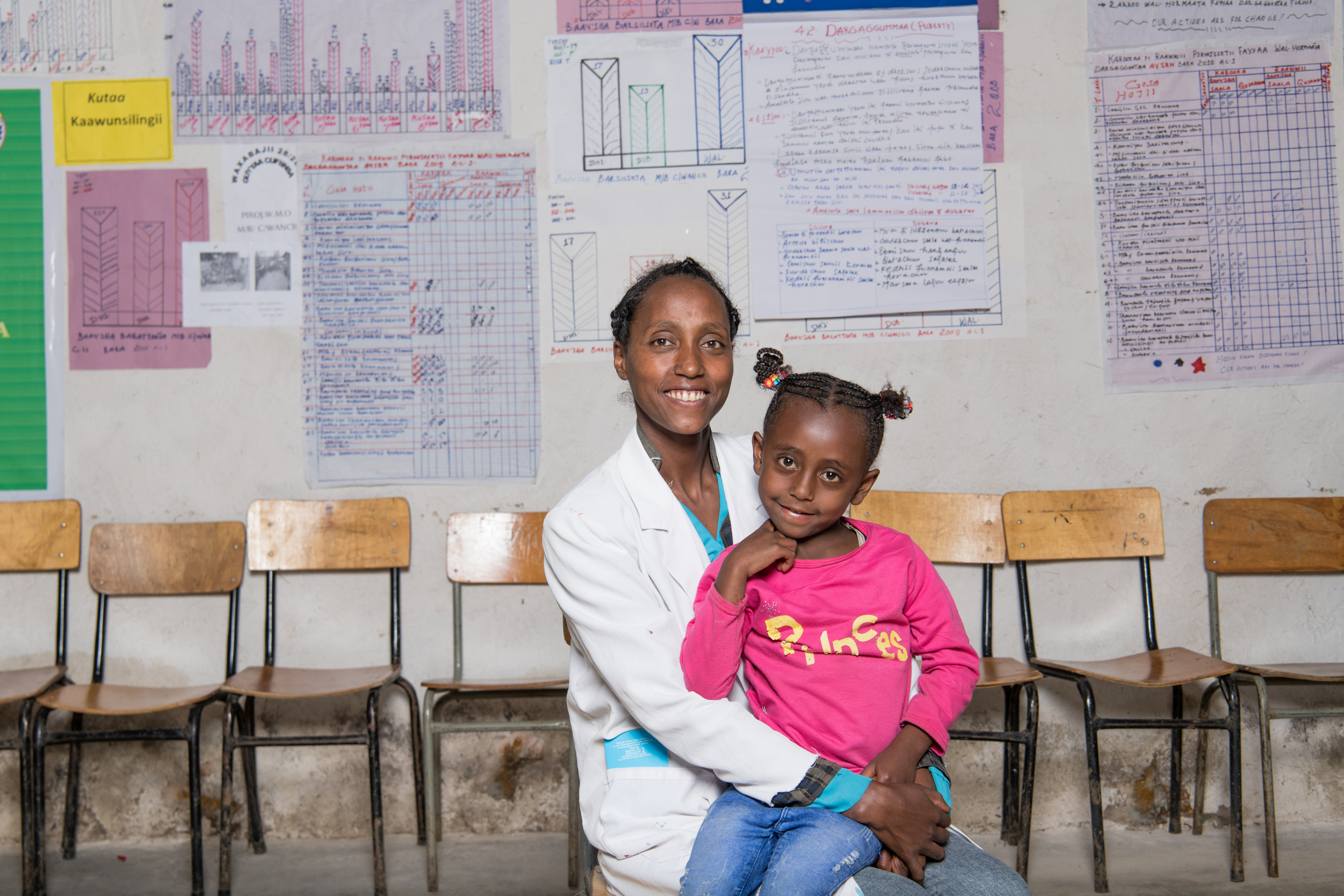 A young girl and her mother smiles for a photo in a classroom in Ethiopia.